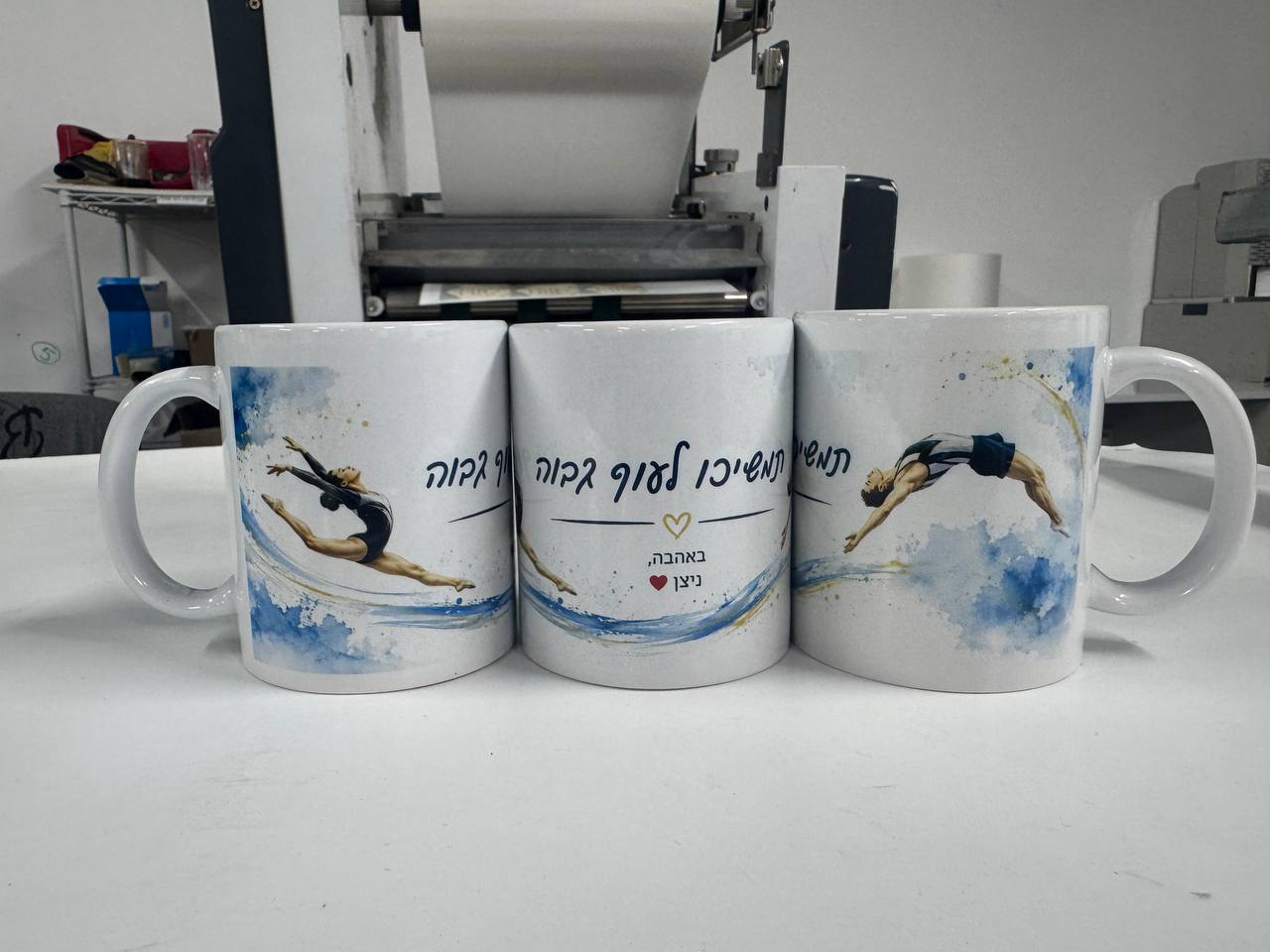 שלושה ספלים לבנים עם ידיות והדפסים צבעוניים